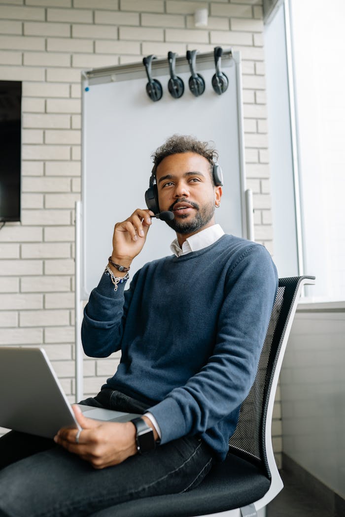 who-we-are Confident young call center agent working with laptop and headset in a modern office setting.
